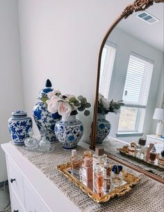 a mirror and some vases on top of a dresser