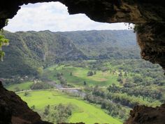 the view from inside a cave looking down on a valley