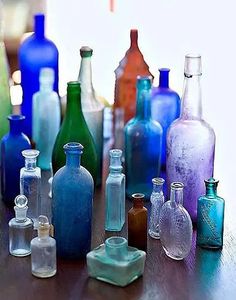 there are many different colored glass bottles on the table