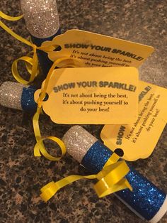 some blue and yellow sparklers are laying on the ground next to a tag that says show your sparkle