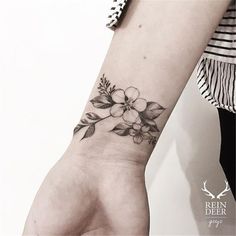 a woman's hand with a flower tattoo on the left wrist and an armband