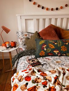 a bed with pillows and blankets on top of it in front of a night stand