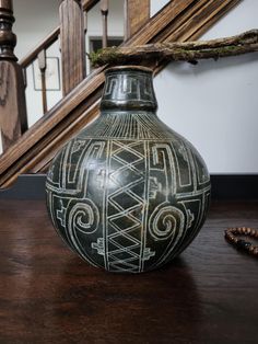 a vase sitting on top of a wooden table next to a banister and stairs