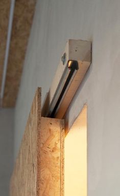 a light that is on in the corner of a wall next to a piece of wood