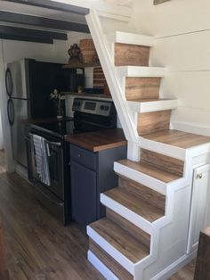 the stairs are made from wood and have white railings on each side, along with black appliances