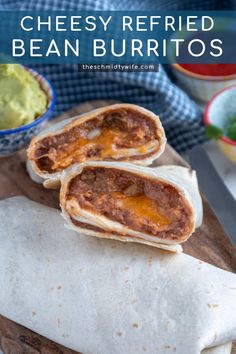 two burritos on a cutting board with guacamole in the background