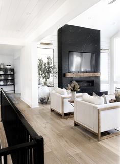 a living room filled with white furniture and a flat screen tv mounted to the wall