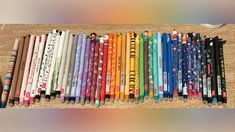 many different colored pencils lined up on a wooden table with an eraser in the middle