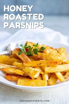 a white plate topped with french fries covered in parmesan cheese and garnished with herbs