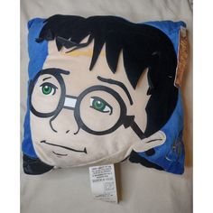 a harry potter pillow with green eyes and glasses on it's face, sitting on a bed