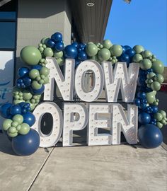 a sign that says now open with balloons