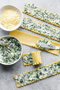 some ravioli with cheese and spinach on them next to a bowl of grated parmesan cheese