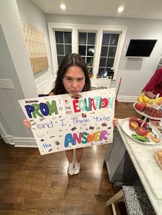 a girl holding up a sign that says prom and i think none the answer