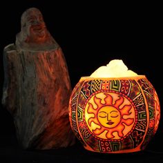 a lit candle sitting on top of a wooden stump next to a carved sun face