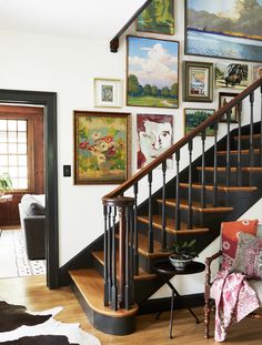 a stair case with pictures on the wall above it and a chair next to it