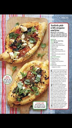 two small pizzas sitting on top of a wooden cutting board