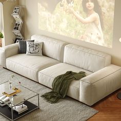 a living room with a white couch and coffee table in front of a large screen