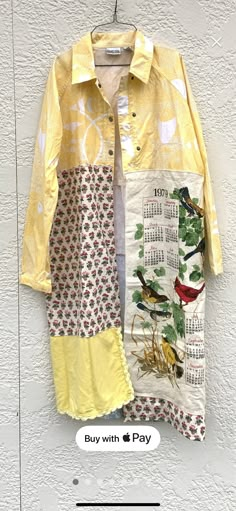 a yellow shirt with birds on it hanging from a hook in front of a white wall