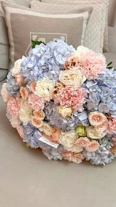 a bouquet of flowers sitting on top of a table next to two pillows and a pillow