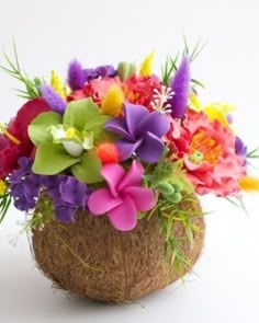 an arrangement of colorful flowers in a coconut shell