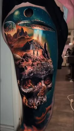 a man's leg with an alien landscape on it and a skull in the foreground