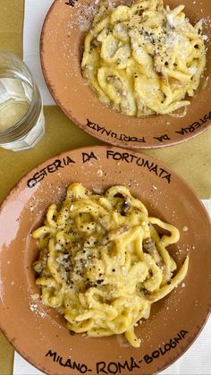 two brown plates filled with pasta on top of a table