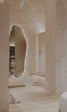 a room with white walls and wooden flooring next to a round mirror on the wall