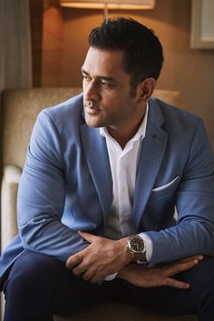 a man in a blue suit sitting on a chair with his arms crossed and looking off to the side