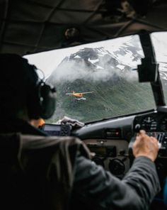 two pilots in the cockpit of an airplane flying over mountains