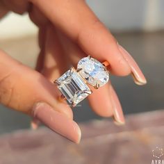 a woman's hand holding an engagement ring with two stone stones on the side