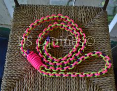 the pink and green bracelet is sitting on top of a wicker chair with a rope