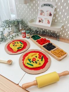 two pizzas with different toppings on them sitting on top of a counter next to a rolling pin