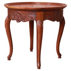 an oval wooden table with carvings on the top and bottom, sitting against a white background