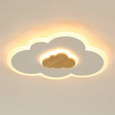 a white cloud shaped light fixture in the ceiling with a wooden disk on it's center