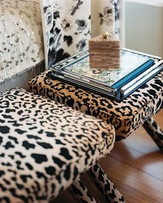 a leopard print chair and ottoman with a glass top on it in front of a mirror