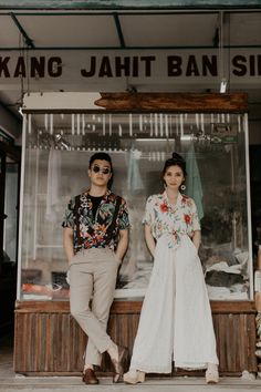 two people standing in front of a food stand with their hands on their hipss