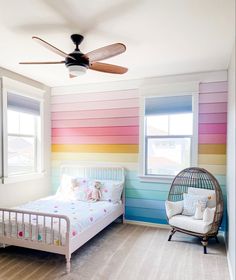 a bedroom with rainbow painted walls and a white bed in the middle, along with a bird cage on the floor