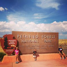 two children standing in front of the petrified forest national park sign on a sunny day