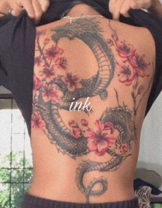 the back of a woman's body with flowers and a dragon tattoo on it