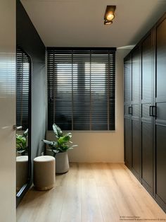 an empty room with wooden floors and black shutters on the windows, along with two planters