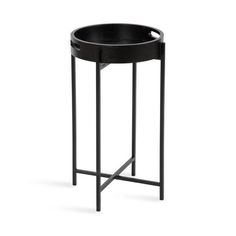 a black round table with metal legs and a tray on the bottom that is holding an empty