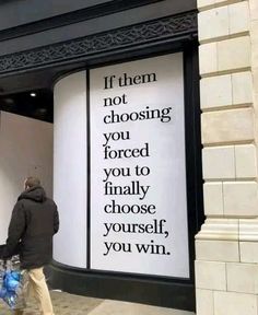 a man walking past a tall advertisement on the side of a building that says if them not choosing you forced to finally choose yourself, you'll