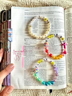 an open bible with beads and letters on it, next to a person's hand