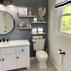 a white toilet sitting under a bathroom mirror next to a sink and a counter top