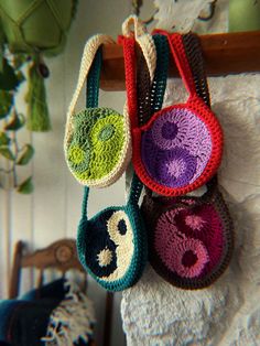 three crocheted purses hanging from a hook on a towel rack in a room