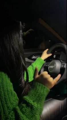 a woman driving a car at night with her hands on the steering wheel