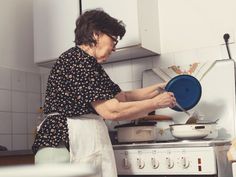 an older woman is washing dishes in the kitchen