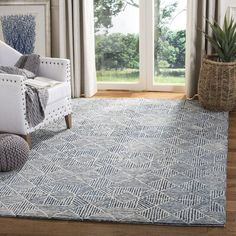 a living room area with a white chair and blue rug in front of large windows