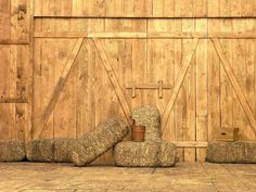 two hay bales sitting in front of a wooden wall