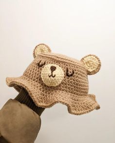 a crocheted bear hat is held up to the camera